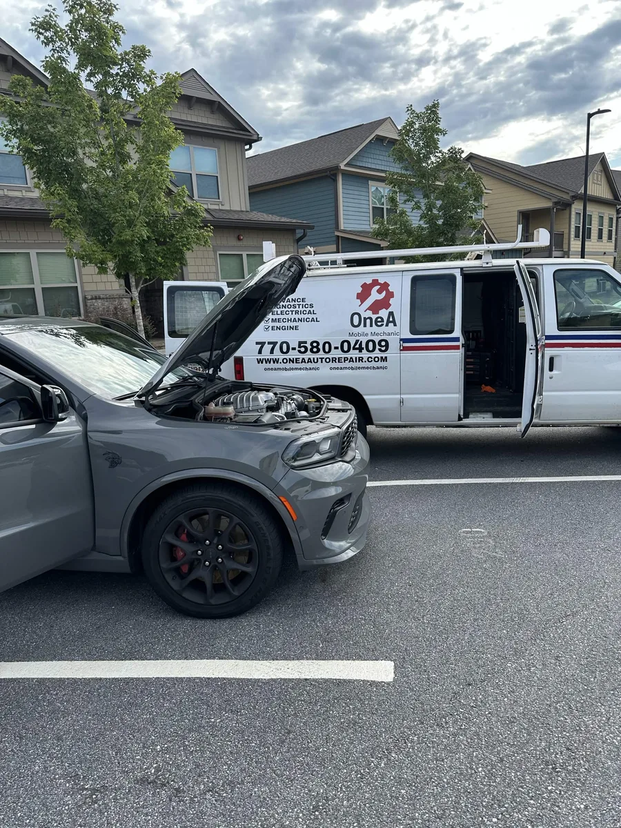 OneA service van beside a gray pickup with its hood open